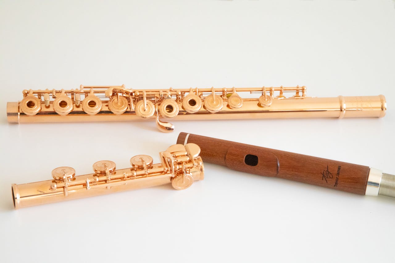 Close-up of elegant copper flutes and a woodwind instrument on a white background.